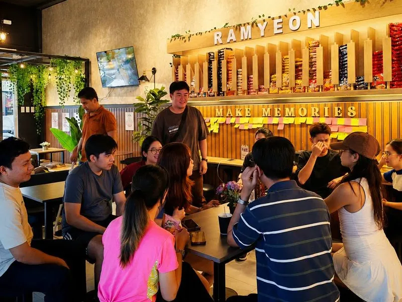 A full room of customers eating and chatting under the ramyeon wall at K-Stop Balanga