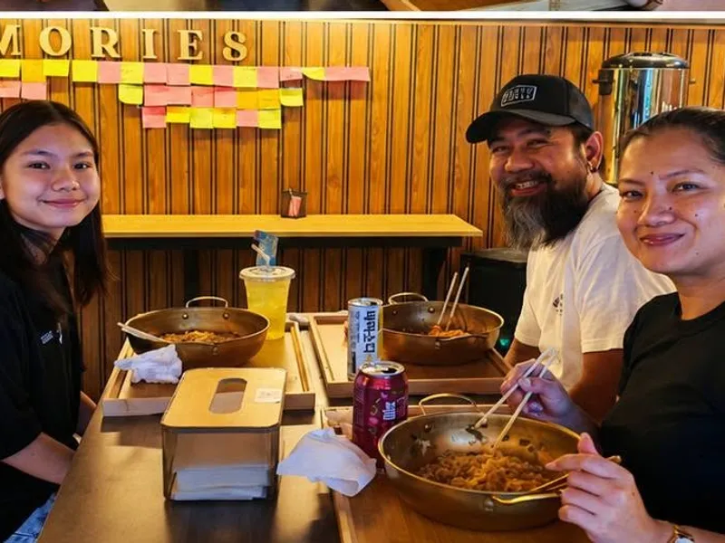Customers with gold hotpots at a table by the MAKE MEMORIES wall