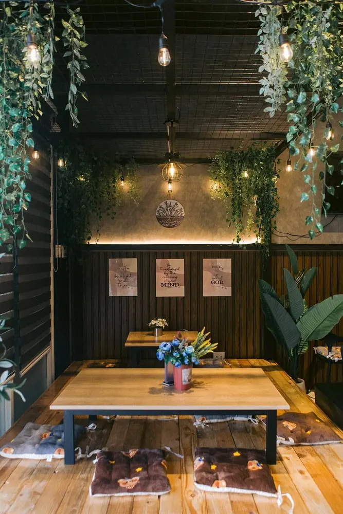 Floor-seating corner at K-Stop with a low wooden table, cushions and hanging plants