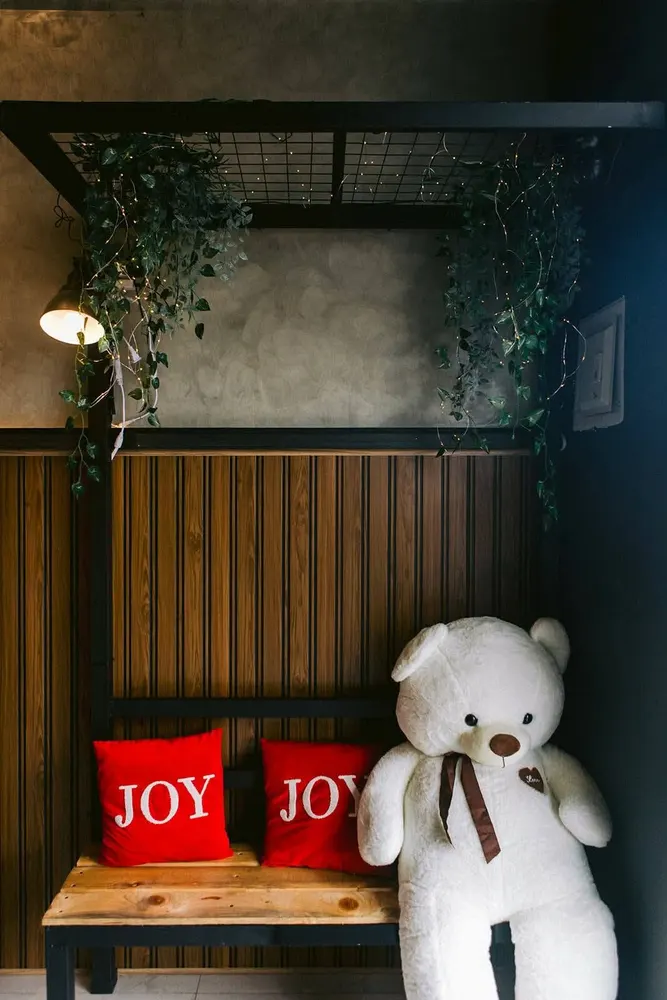 Wooden bench with red JOY pillows and a large white teddy bear in the K-Stop photo corner